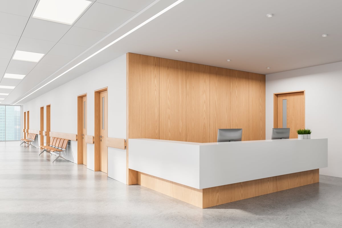Reception area of a modern medical facility with minimalist wood and white interior design